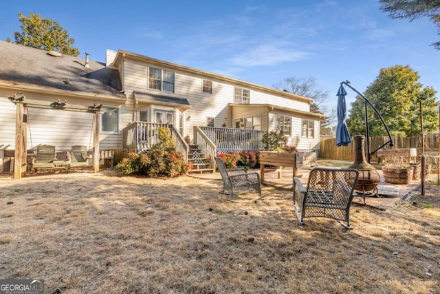 back of property with a wooden deck and a fire pit