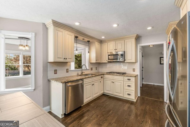 kitchen featuring decorative light fixtures, sink, dark hardwood / wood-style flooring, stainless steel appliances, and cream cabinetry