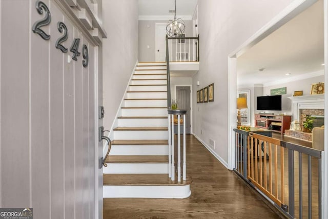 stairs featuring an inviting chandelier, hardwood / wood-style floors, and crown molding