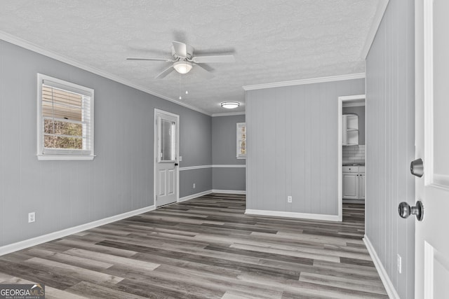 empty room with crown molding, ceiling fan, dark hardwood / wood-style flooring, and a textured ceiling