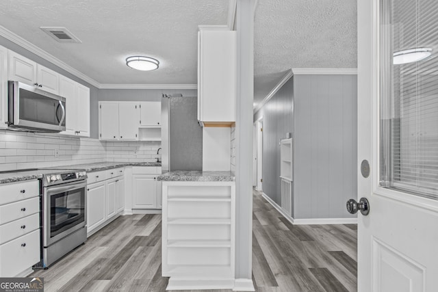 kitchen featuring ornamental molding, appliances with stainless steel finishes, light wood-type flooring, and white cabinets