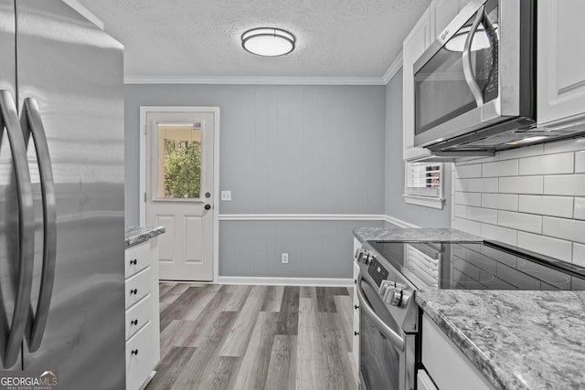 757 Sparta Hwy, Eatonton, GA 31024 - kitchen featuring appliances with stainless steel finishes, white cabinets, wood finished floors, backsplash, and ornamental molding