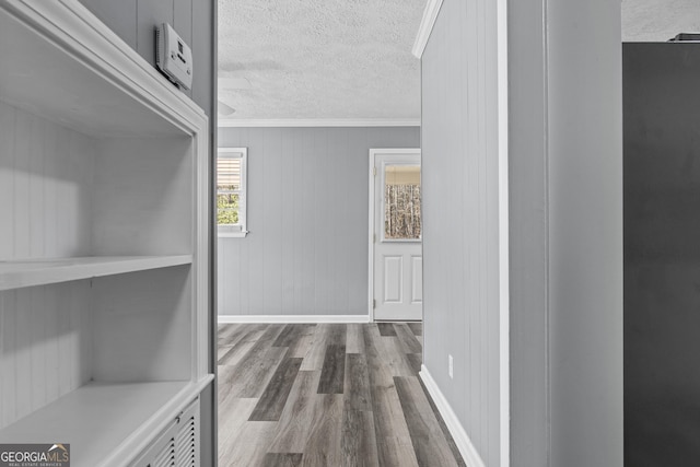 hallway featuring hardwood / wood-style flooring, ornamental molding, and a textured ceiling