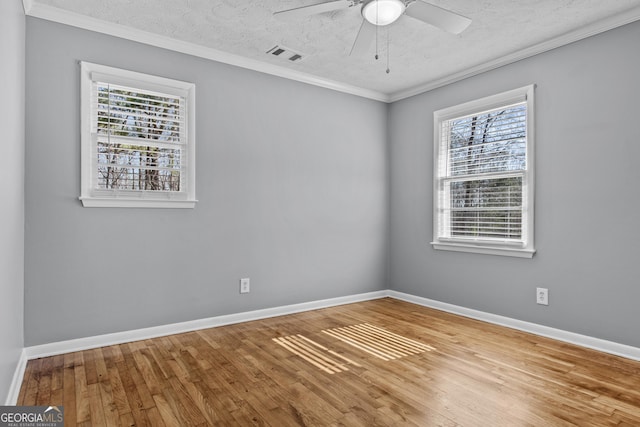 spare room featuring wood-type flooring, ornamental molding, ceiling fan, and a textured ceiling