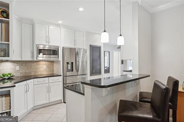 kitchen with light tile patterned floors, appliances with stainless steel finishes, white cabinets, a kitchen bar, and decorative backsplash