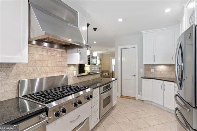 kitchen featuring pendant lighting, light tile patterned floors, appliances with stainless steel finishes, range hood, and white cabinets