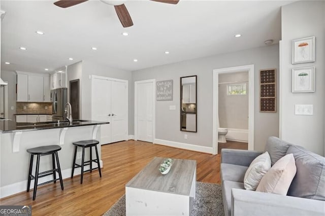 living room with ceiling fan and light wood-type flooring