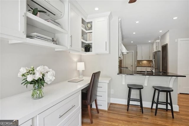 kitchen featuring white cabinetry, a kitchen bar, built in desk, and stainless steel refrigerator