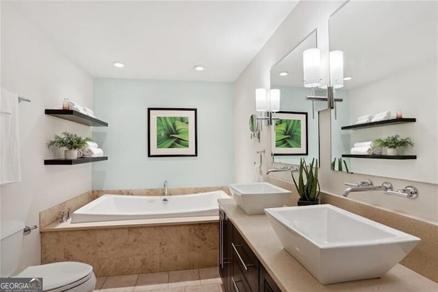 bathroom with vanity, tiled tub, tile patterned floors, and toilet