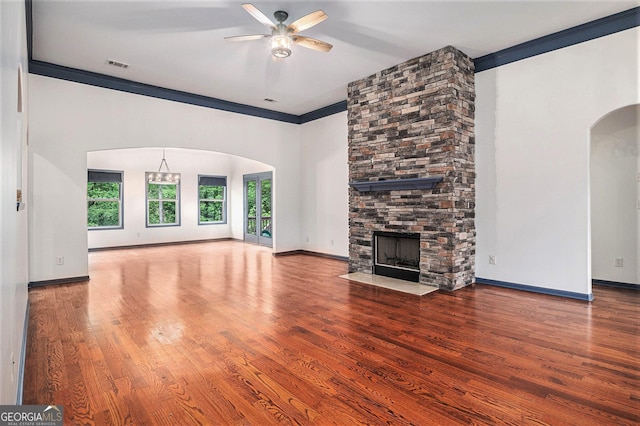 2753 Jubilee Ter, Bethlehem, GA 30620 - unfurnished living room with arched walkways, a ceiling fan, a stone fireplace, ornamental molding, and wood finished floors