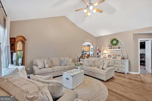 living room featuring ceiling fan, high vaulted ceiling, a healthy amount of sunlight, and light wood-type flooring