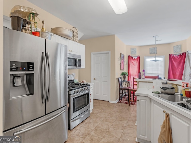 kitchen with light tile patterned flooring, appliances with stainless steel finishes, sink, white cabinets, and hanging light fixtures