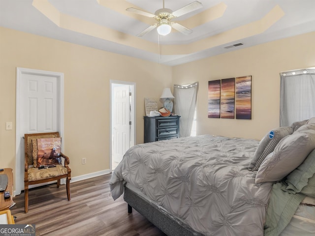 bedroom with a tray ceiling and hardwood / wood-style flooring