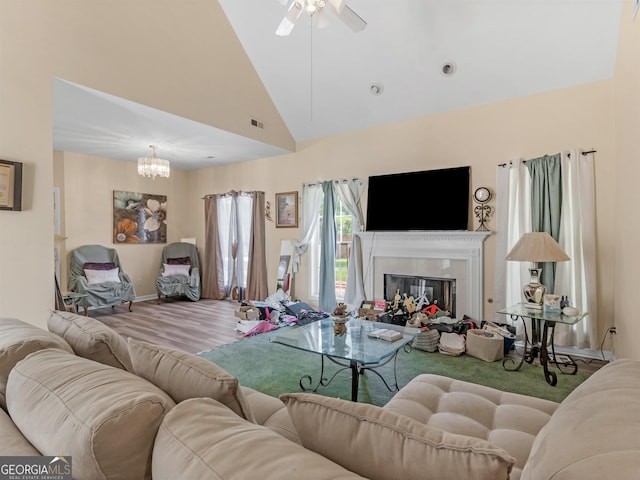 living room with ceiling fan with notable chandelier, high vaulted ceiling, and hardwood / wood-style flooring