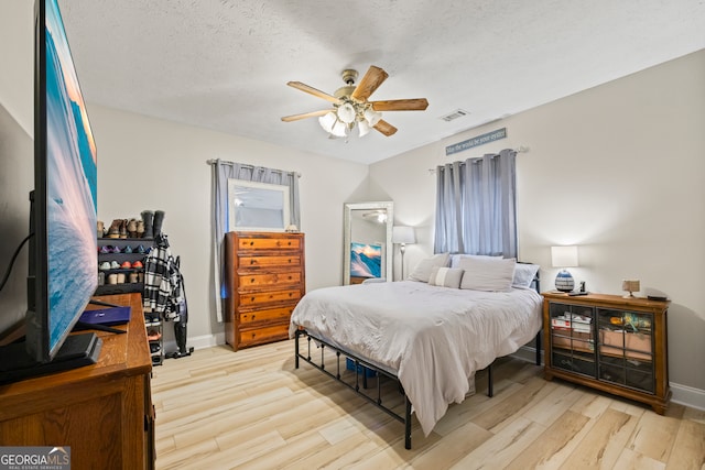 bedroom featuring ceiling fan, light hardwood / wood-style flooring, and a textured ceiling