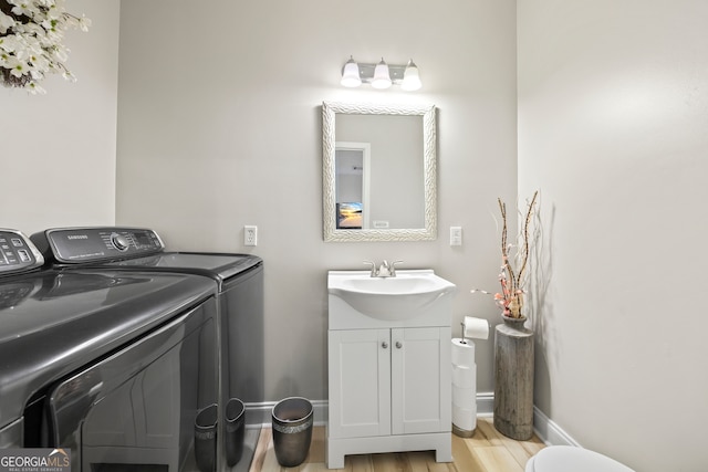 laundry room featuring washing machine and dryer, sink, and light wood-type flooring