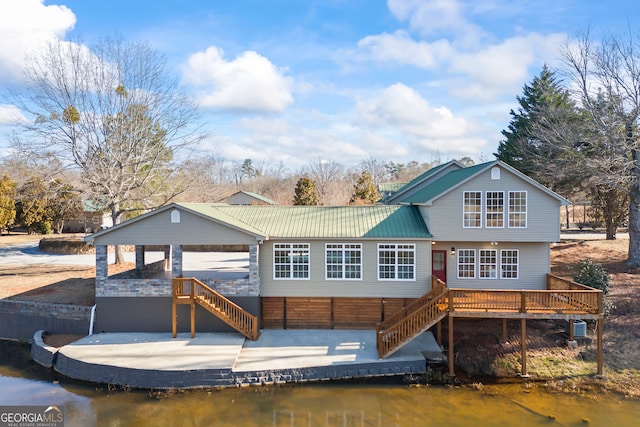 back of property featuring a deck with water view