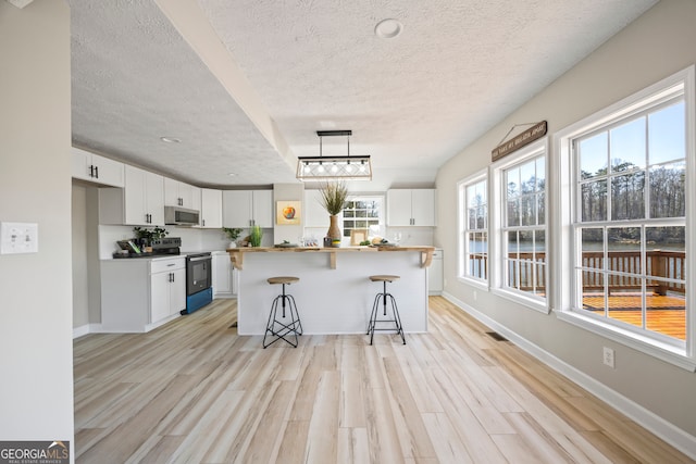 kitchen featuring electric stove, white cabinetry, a center island, a kitchen bar, and decorative light fixtures