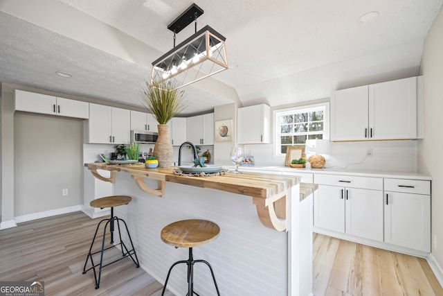 kitchen with a center island, a breakfast bar, butcher block countertops, and white cabinets