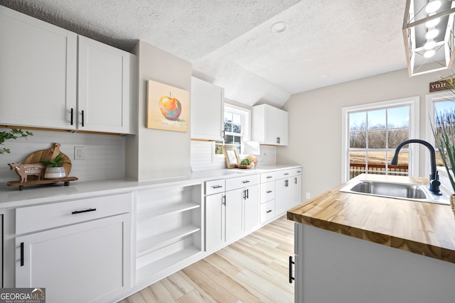 kitchen with sink, white cabinetry, tasteful backsplash, wood counters, and light wood-type flooring