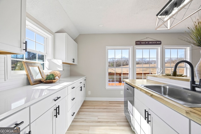 kitchen with stainless steel dishwasher, sink, a textured ceiling, and white cabinets