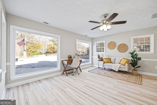 sitting room featuring ceiling fan, a textured ceiling, and light hardwood / wood-style flooring