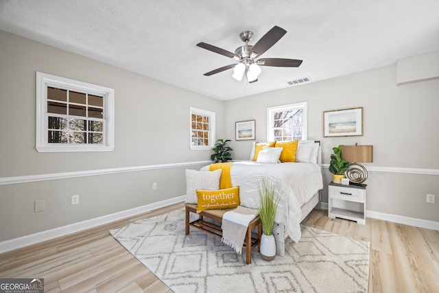 bedroom with ceiling fan, a textured ceiling, and light wood-type flooring