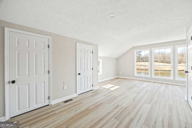 bonus room featuring vaulted ceiling, a textured ceiling, and light wood-type flooring