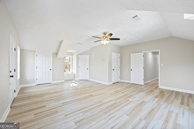 unfurnished living room with ceiling fan, lofted ceiling, a textured ceiling, and light wood-type flooring