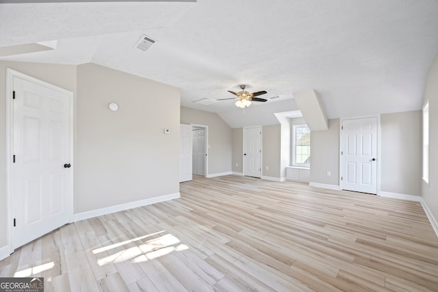 interior space featuring lofted ceiling, ceiling fan, light hardwood / wood-style floors, and a textured ceiling