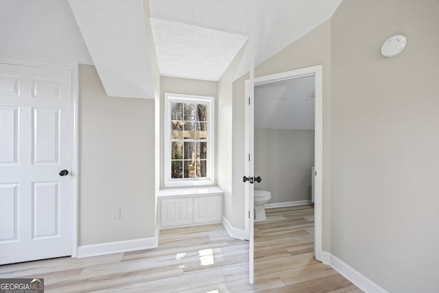 bathroom featuring vaulted ceiling, toilet, hardwood / wood-style floors, and a textured ceiling