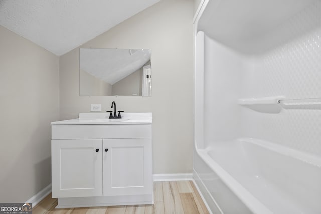 bathroom with vanity, lofted ceiling, wood-type flooring, and a textured ceiling