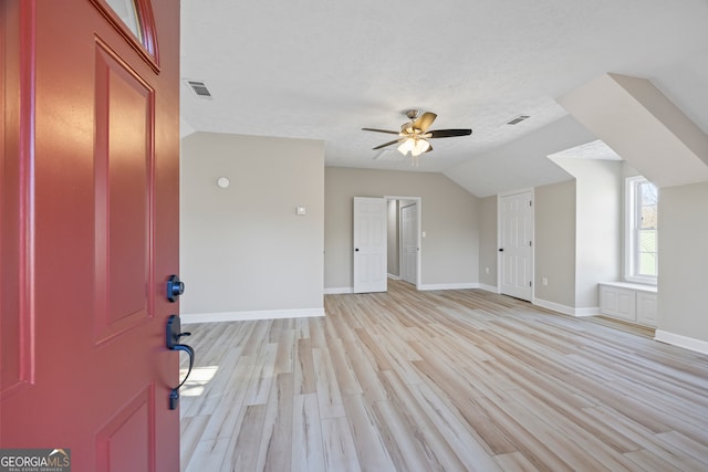 interior space featuring ceiling fan, lofted ceiling, a textured ceiling, and light hardwood / wood-style floors