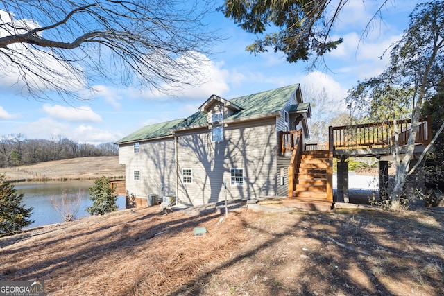 view of side of home with a deck with water view and central air condition unit