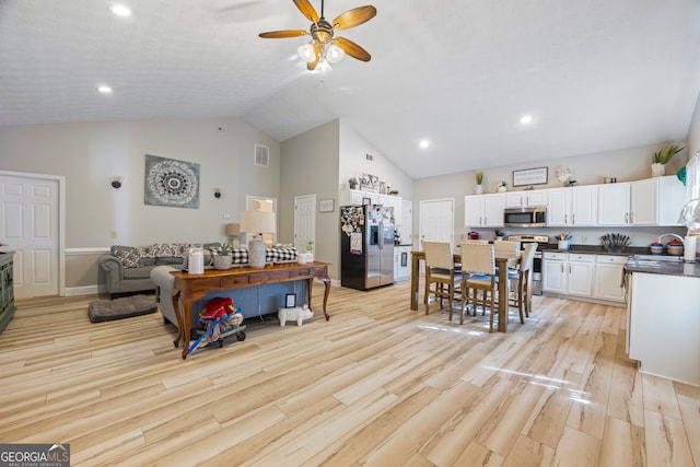 interior space with ceiling fan, high vaulted ceiling, and light wood-type flooring