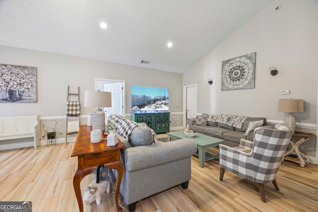 living room featuring high vaulted ceiling and light hardwood / wood-style flooring