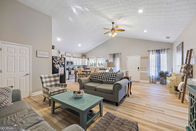 living room featuring ceiling fan, high vaulted ceiling, a textured ceiling, and light wood-type flooring