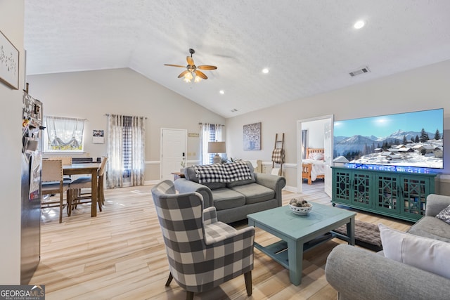 living room featuring ceiling fan, high vaulted ceiling, a textured ceiling, and light hardwood / wood-style flooring