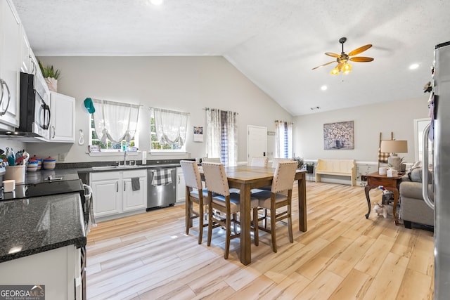 dining area featuring ceiling fan, sink, high vaulted ceiling, and light hardwood / wood-style flooring