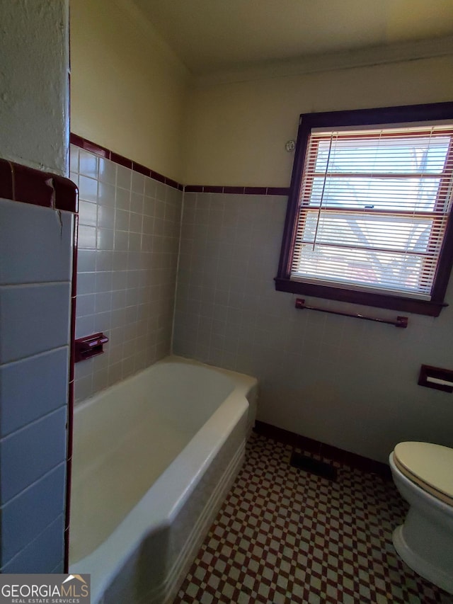 bathroom featuring ornamental molding, toilet, and a bathtub