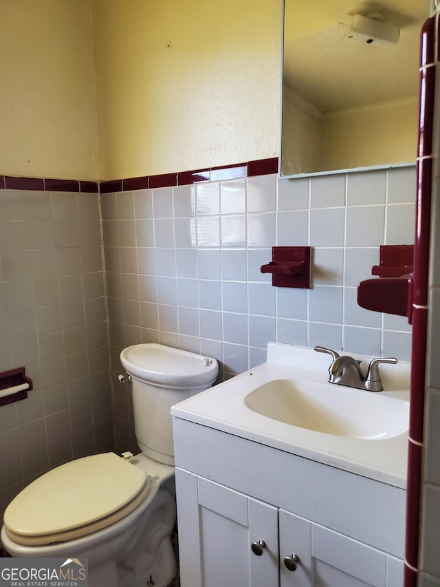 bathroom featuring vanity, tile walls, and toilet