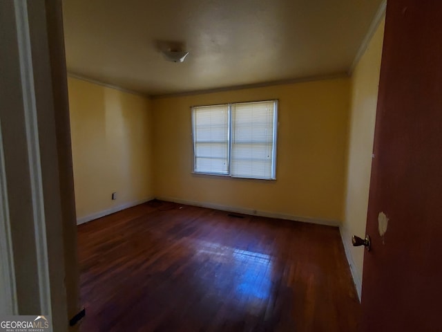 spare room with ornamental molding and dark hardwood / wood-style floors