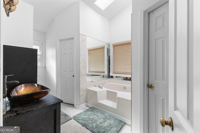 bathroom with vanity, lofted ceiling with skylight, and a bathtub