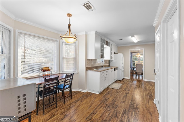 kitchen with tasteful backsplash, white cabinetry, ornamental molding, and dark hardwood / wood-style flooring