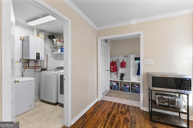 washroom featuring washing machine and dryer, ornamental molding, tankless water heater, and light hardwood / wood-style floors