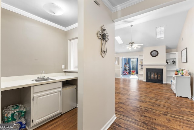 kitchen with sink, crown molding, dark wood-type flooring, ceiling fan, and white cabinetry