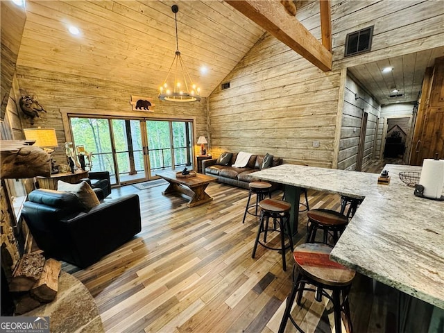 living room with high vaulted ceiling, wooden walls, hardwood / wood-style flooring, a notable chandelier, and wooden ceiling