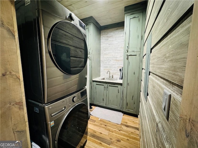 washroom with sink, cabinets, stacked washer and clothes dryer, wood ceiling, and light hardwood / wood-style floors