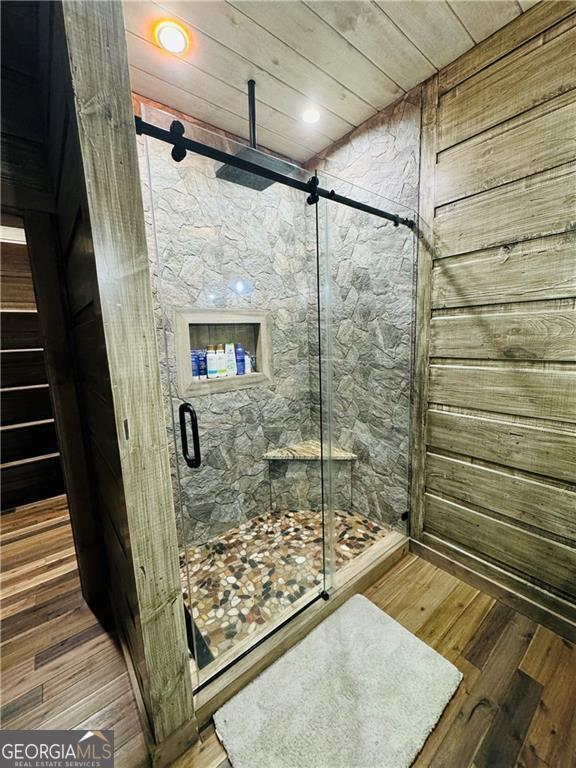 bathroom with hardwood / wood-style flooring and a shower with shower door