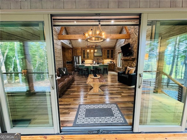 interior space featuring an inviting chandelier, vaulted ceiling with beams, and wood-type flooring